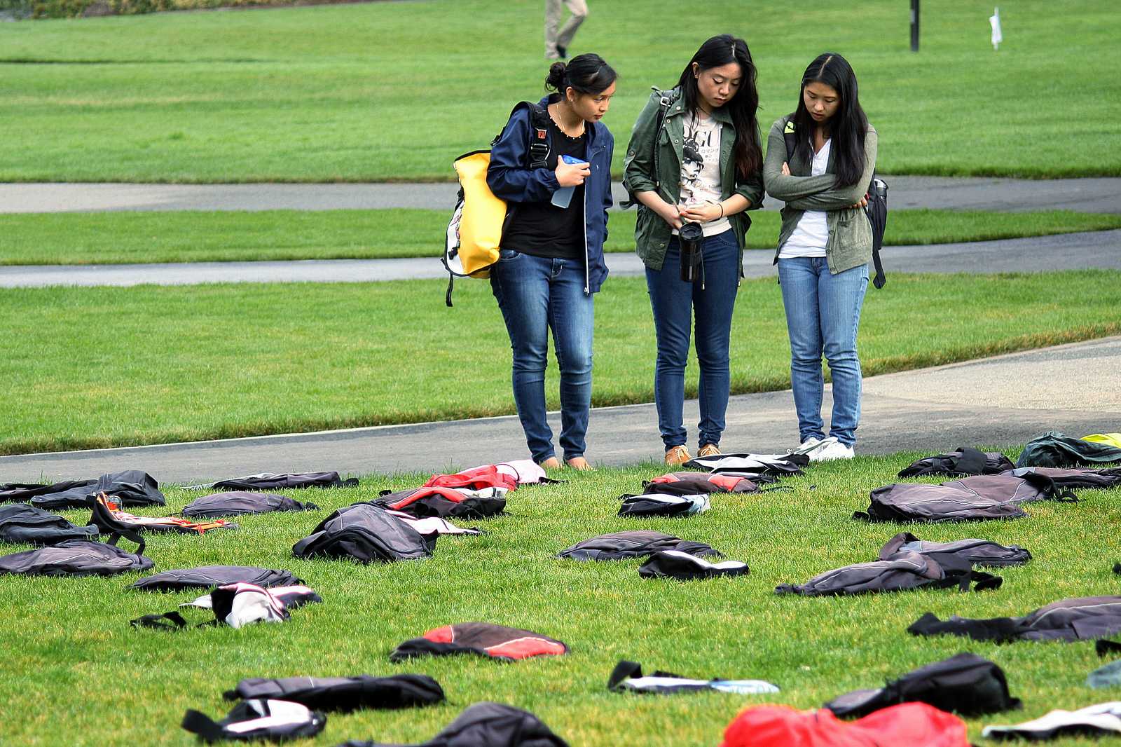 Sophomore nursing students Monique Obiniana (left), Michelle Young (center) and Ashley Chan (right) read a story about one of the 1,100 backpacks placed on the lawn in the Quad which signify the number of students who commit suicide each year. The installation was part of SF State's first suicide prevention conference Friday, Oct. 18, 2013. Photo by Tony Santos / Xpress