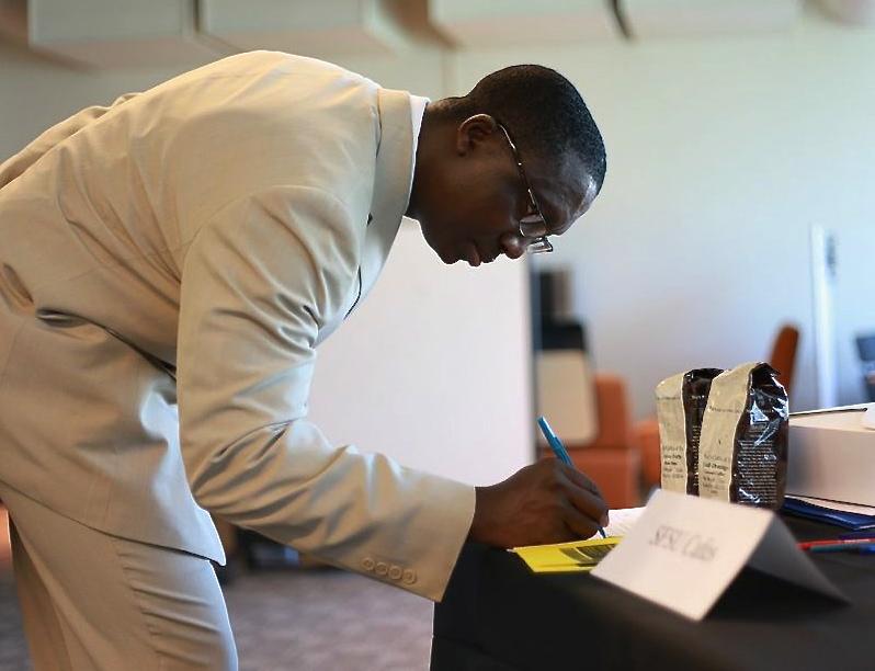 Tamba Sellu, Chico State alumni, writes his name at SFSU Cafes booth at the Hospitality Career Fair Thursday, March 20, 2014. Photo by Ryan Leibrich / Xpress