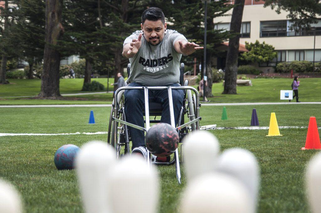Alfredo Andrade, a kinseology major, gets a hands on experience on what its like to be a wheelchair-user whie playing accessible bowling on the lawn at Malcom X Plaza during SF States Accessible Adventure Day Tuesday, April 15. Photo by Jessica Christian / Xpress