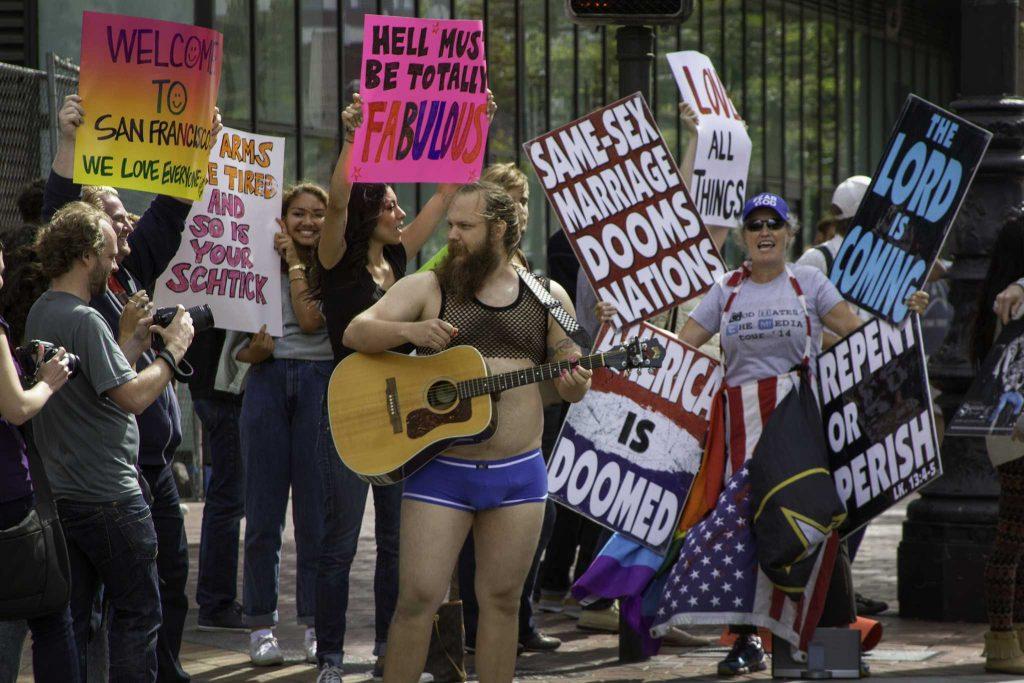 Activist Jon Allen plays a guitar in front of demonstrators in front of the Twitter offices on Market Street on Aug. 12. Photo by Frank Ladra.