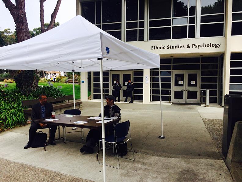 Campus representatives sit at an information booth providing class relocation information outside the Ethnic Studies and Psychology Building Thursday, Aug. 28.