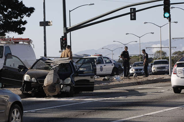 Police officers survey the site of a car accident south of the 19th Avenue and Junipero Serra Boulevard intersection on Monday, Sept. 15, 2014. According to Officer Tad Yamacuchi of the San Francisco Police Department, a 20 year old male, driving the black Lexus, ran into a city light pole on his way to work, when he did not make the slight right. Daniel Porter / Xpress.