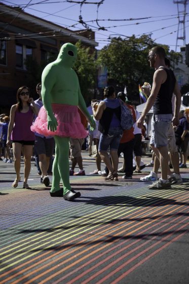 A costumed fair attendee walks over the Castro neighborhood's newly installed rainbow crosswalk as people walk up and down the street at the Castro Street Fair in San Francisco Sunday, Oct. 5, 2014. Frank Ladra / Xpress.