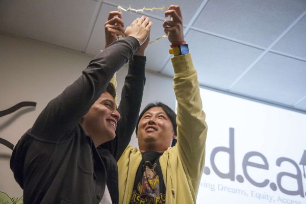 Danny Chau (right) fits Diego Castro (left) through a cut up index card to demonstrate the idea of possibilities during an IDEAS meeting in the library Wednesday, Nov. 12, 2014. Martin Bustamante/Xpress.