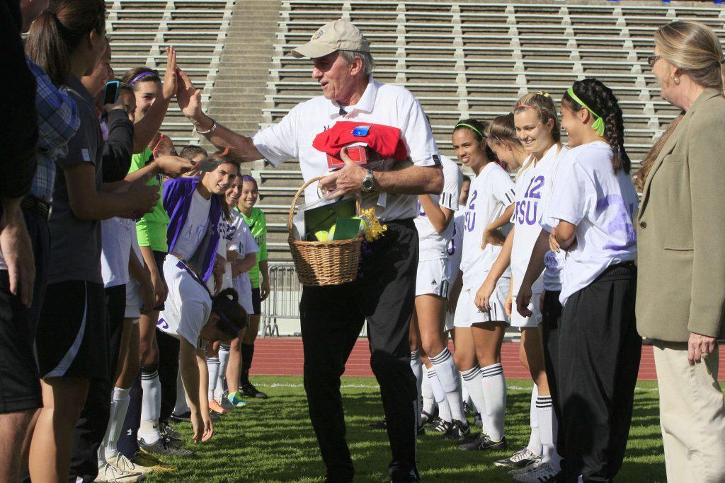 Jack Hyde high-fives a player from the girls soccer team, while he holds presents the team got for him. Coach of the womens soccer team at SF State, Jack Hyde, is retiring this season, so the team made Oct. 22 Coach Jack Hyde Day, right before the girls soccer team at Cox Stadium in San Francisco, Calif., on October 22, 2014.