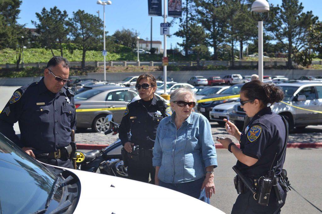 Police interview an elderly woman who struck a mother and daughter in front of The City Sports Club at the Stonestown Galleria Wednesday, March 18. (Helen Tinna / Xpress)