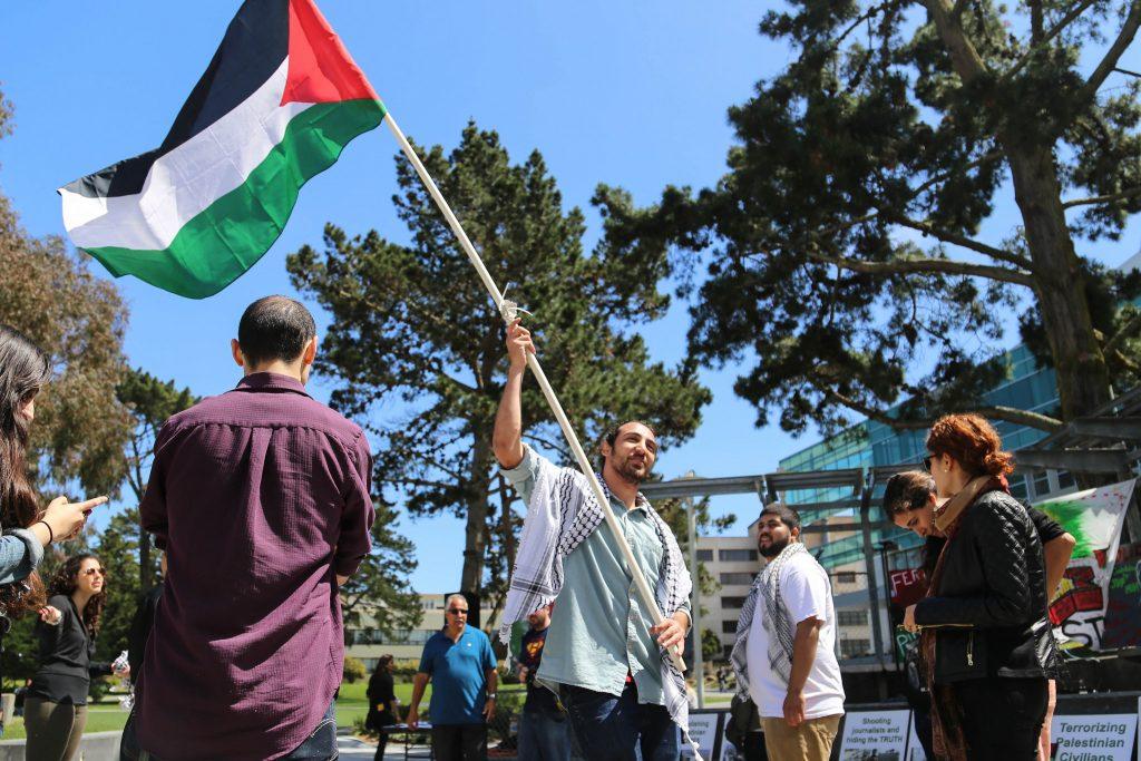 A General Union of Palestine Students, GUPS, member Awwad Yasin waives the Palestinian flag during the Israeli Apartheid Week Rally in Malcolm X Plaza Friday, April 17. (Zhenya Sokolova / Xpress)
