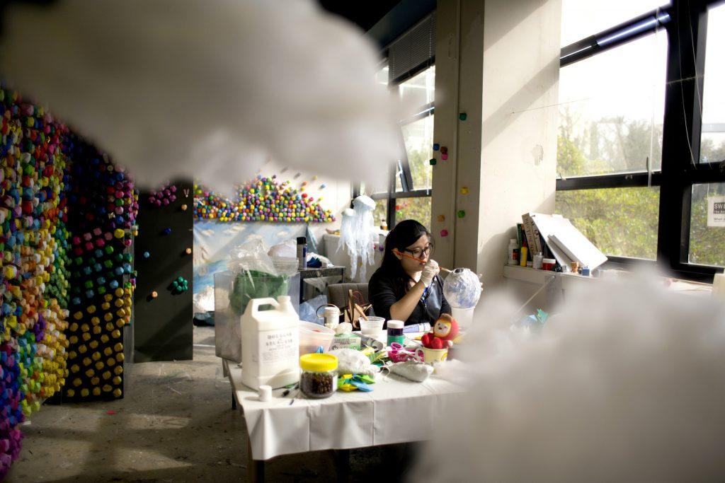 Shan Jiang fine arts graduate student paints a toy fish in her studio on Tuesday March 10, part of her recent project of sea world creatures. (Emma Chiang/ Xpress)