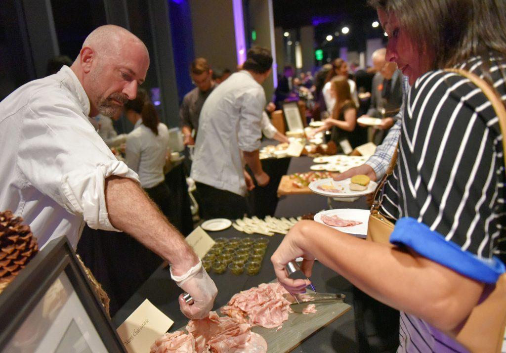 Tim Shaw, left, chef instructor of Hospitality and Tourism Management in the College of Business, serves during Taste of the Bay 2015, hosted by SF State’s Hospitality and Tourism Management students, at City View at Metreon in downtown San Francisco Wednesday, Nov. 18, 2015. (Qing Huang / Xpress)