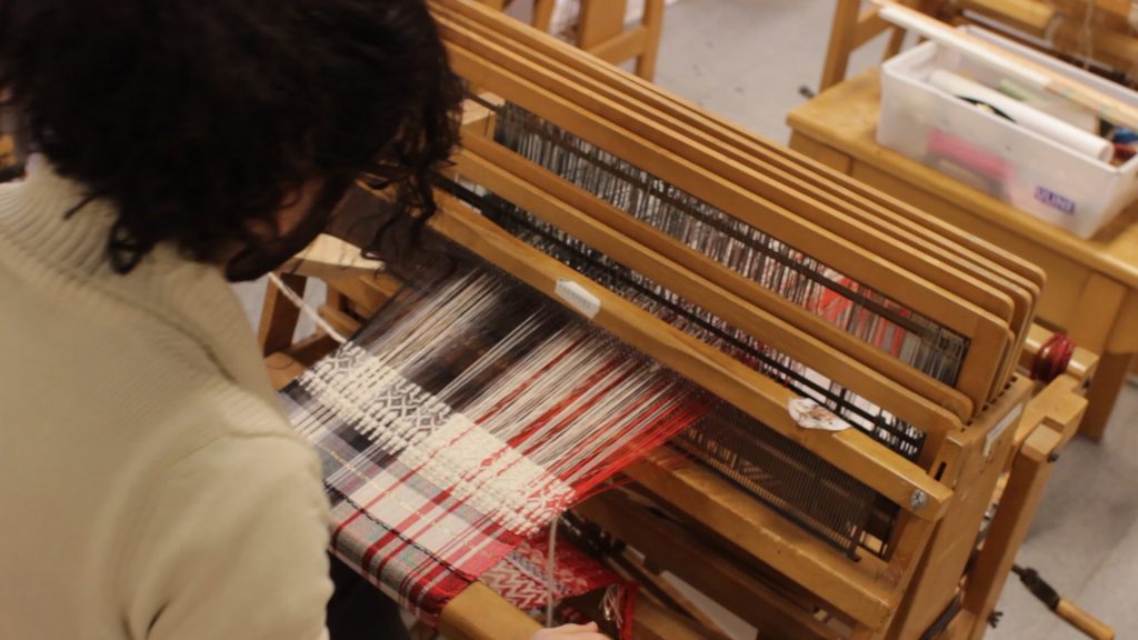 Kilian Farrell-Alvarado, studio art major is weaving a scarf for his final presentation. Friday Dec. 11, 2015 (Screenshot by Angelica Williams / Xpress)
