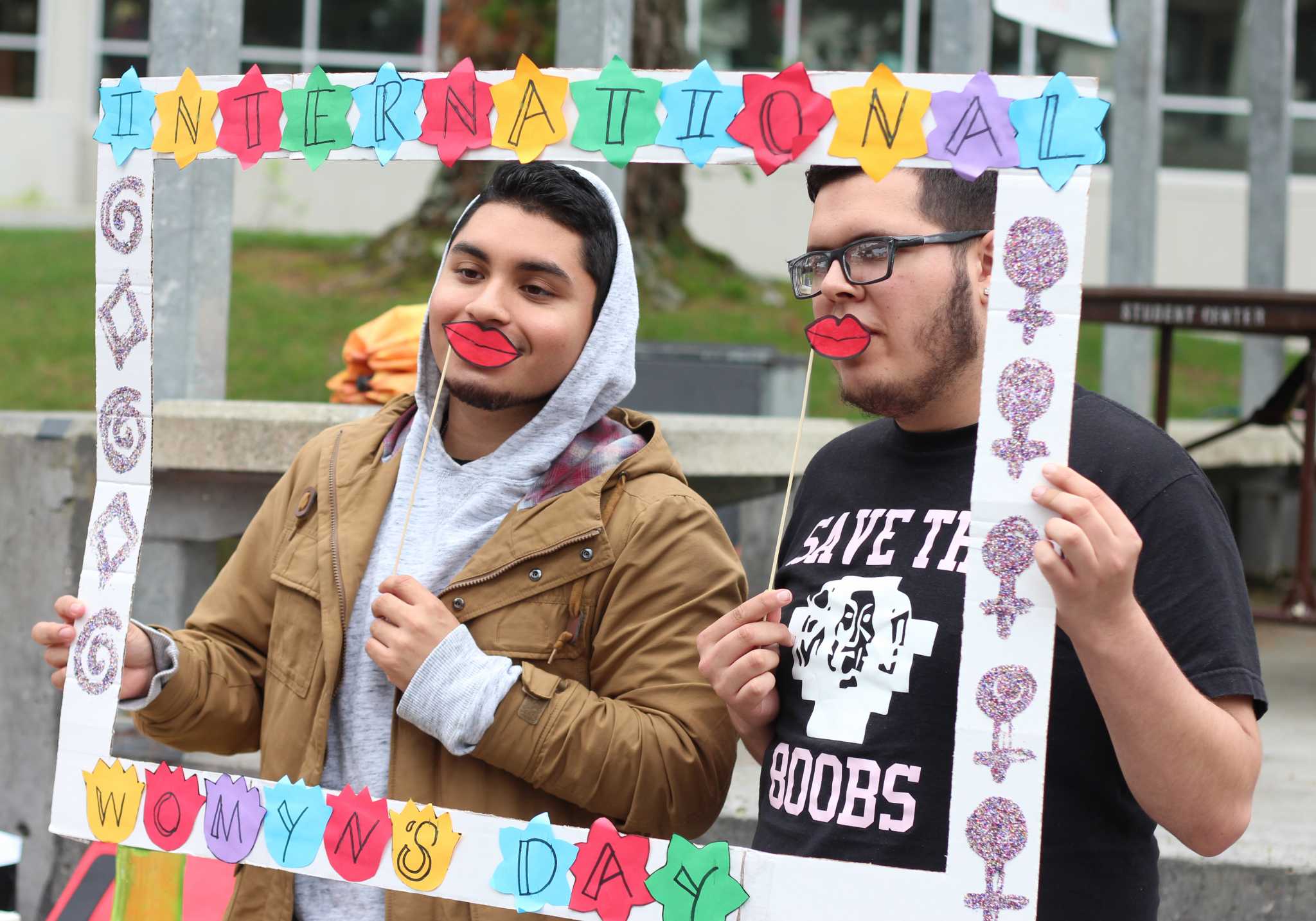 ohn Rivera, (left) marketing major, and Arturo Gomez (right) hospitality major, coordinators from La Raza, promote International Womens Day during an event held in Malcolm X Plaza in which students performed spoken word and poems, and multiple campus organizations did tabling and provided games for students to play, Tuesday, Mar. 8, 2016. (Alex Kofman / Xpress)