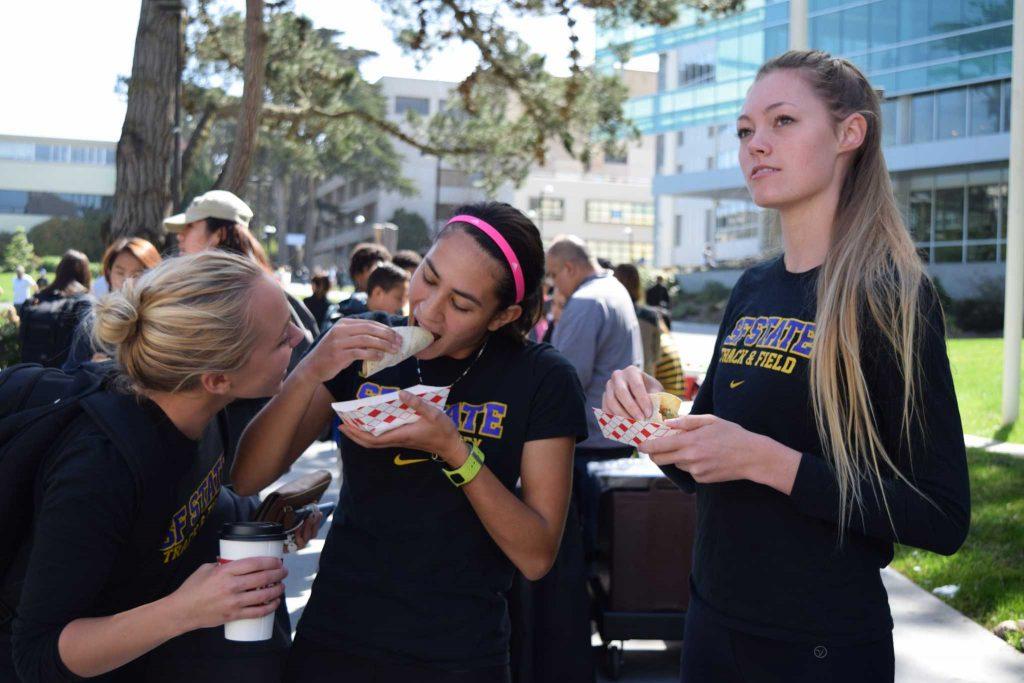 SF State Track and Field team members (left to right) Jacqueline Foley, Sophie Tait and Camille Hansen enjoy free Taqueria Girasol tacos on SF States Founders Day, Tuesday, Mar. 15, 2016. (Gabriela Rodriguez / Xpress)