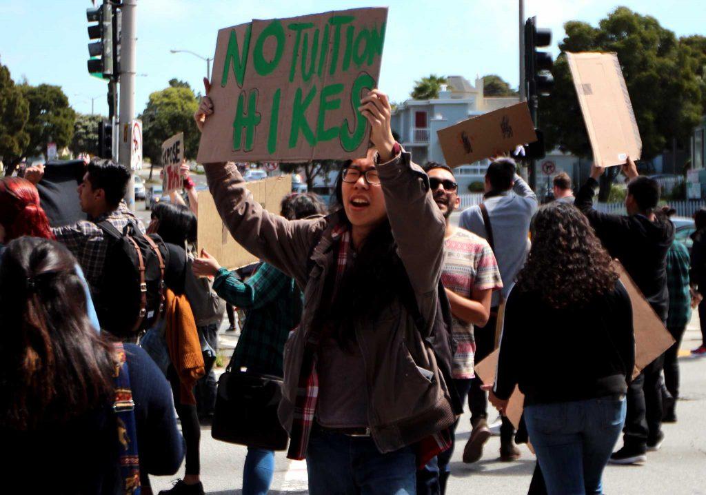 SF State Sociology student, Gary Pei, holds a sign as he crosses the street during a rally in which students came together to bring attention to a variety of issues happening on the SF State campus on 19th and Holloway in San Francisco, CA on Wednesday, April, 13, 2016. (Alex Kofman / Xpress)