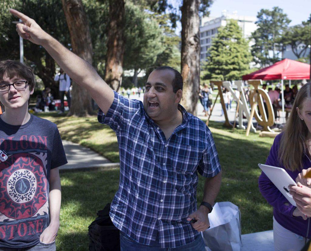 SF State student John Ayoub, the Young Republicans group leader, points toward the ethnic studies rally to draw attention to the fact that they were playing FTD, a song by rappers Nipsey Hussle and YG at Malcolm X Plaza on Tuesday, April. 5. (Ryan Zaragoza / Xpress)