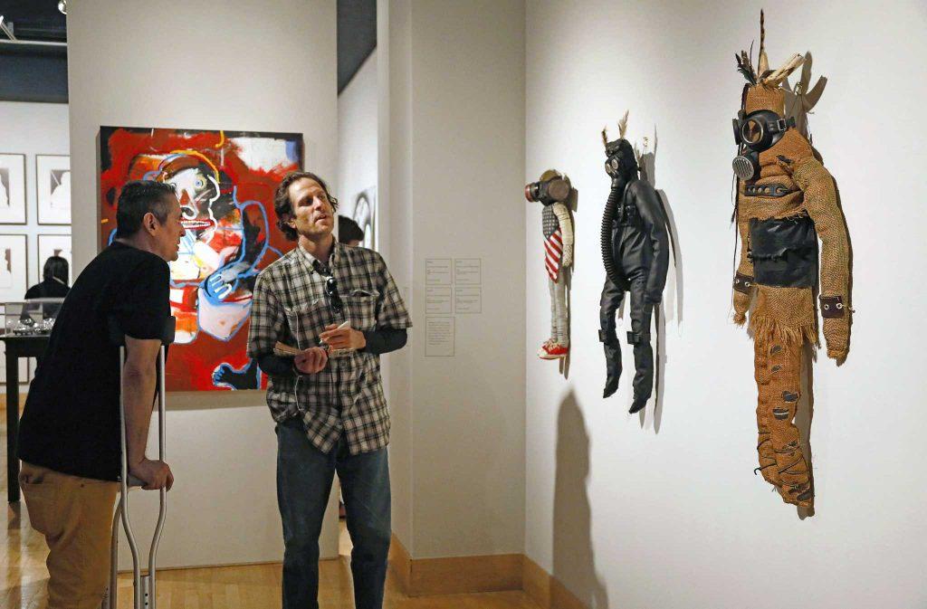  Kevin “Mooshka” Catawho talks to David Kertzman about his kachinas at the reception of the When I Remember, I See Red exhibit at the Fine Arts Gallery on Saturday, Sept. 17, 2016.