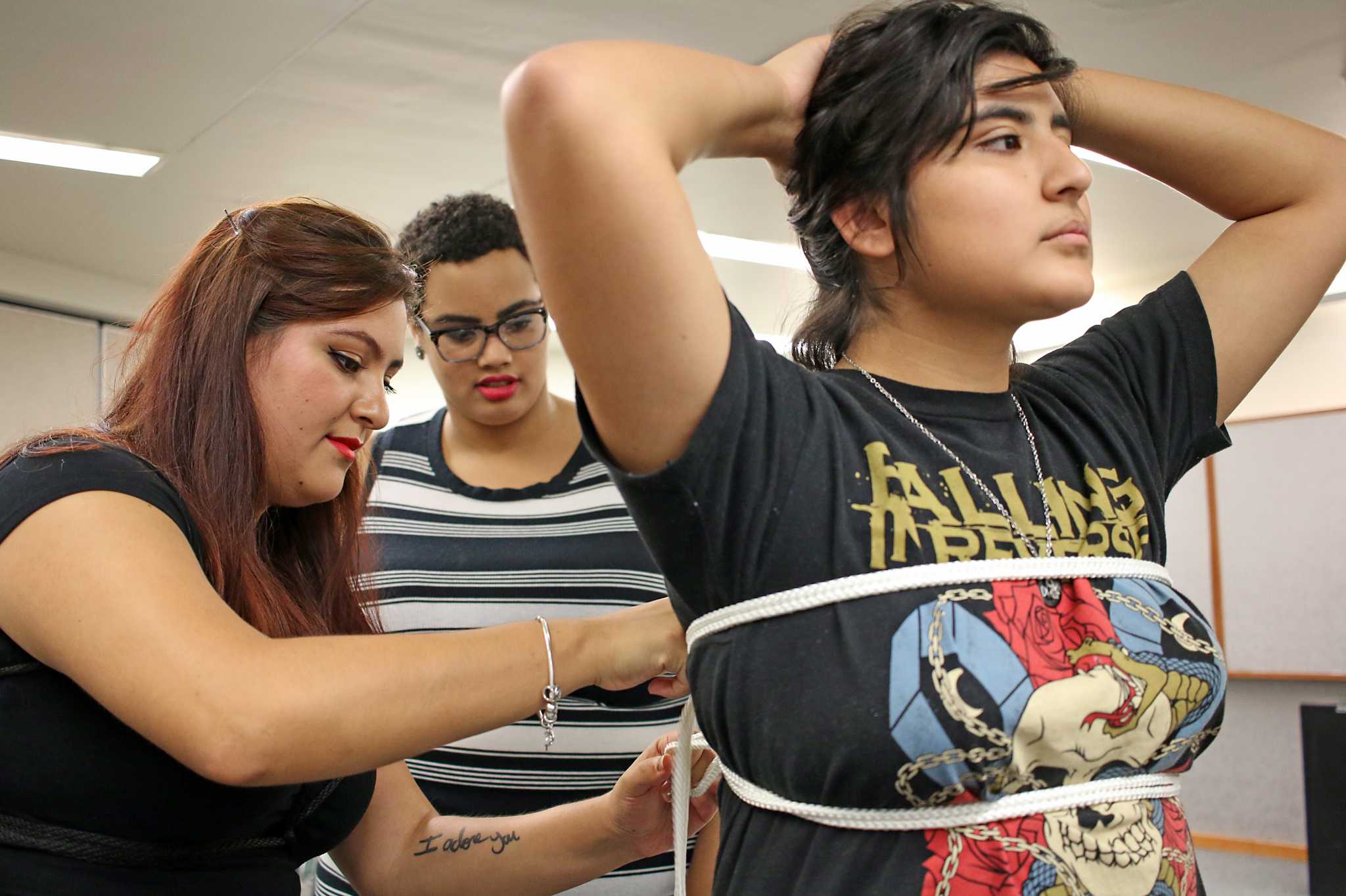 SF State’s Education and Referral Organization for Sexuality director Reyna Aguilar
(left) shows SF State computer science major Maya Chatman (center) how to perform a double limb rope bondage on pre-child adolescent development major Felicia Macedo
(right) during the Playing by the Ropes: Kink & Bondage 101 event in the Rosa Parks Conference Room on Wednesday, Oct. 26, 2016. (George Morin/Xpress)