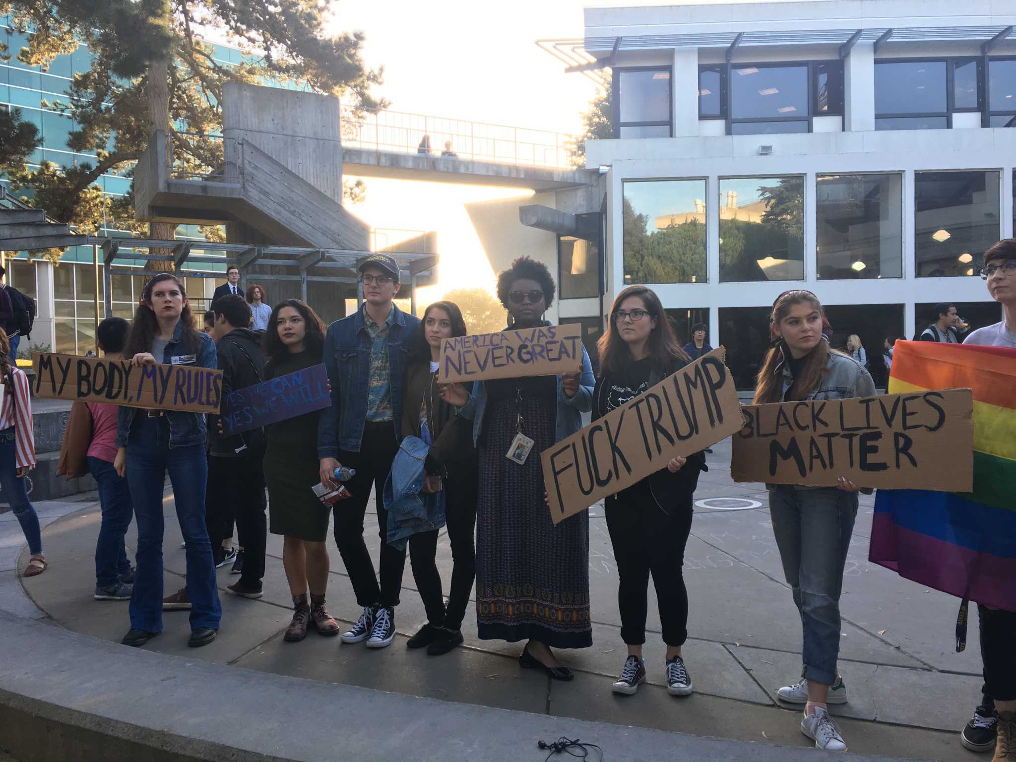 Students pose for a picture in Malcolm X Plaza at SF State holding signs in protest of President Elect Donald Trump winning the presidency on Nov. 9, 2016 (Breanna Reeves/ Xpress).