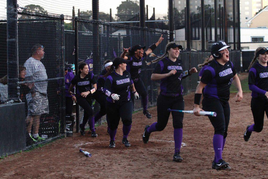 Teammates run out of the dugout to celebrate SF State Gators’ Celeste Adrianos (12) home run, which broke the 3-3 tie against the Cal State East Bay Pioneers in the 7th inning brining in two runs on Saturday, February 11, 2017 in San Francisco, Calif., at SF State. The Gators went on to win 5-3 (Mason Rockfellow/Xpress).