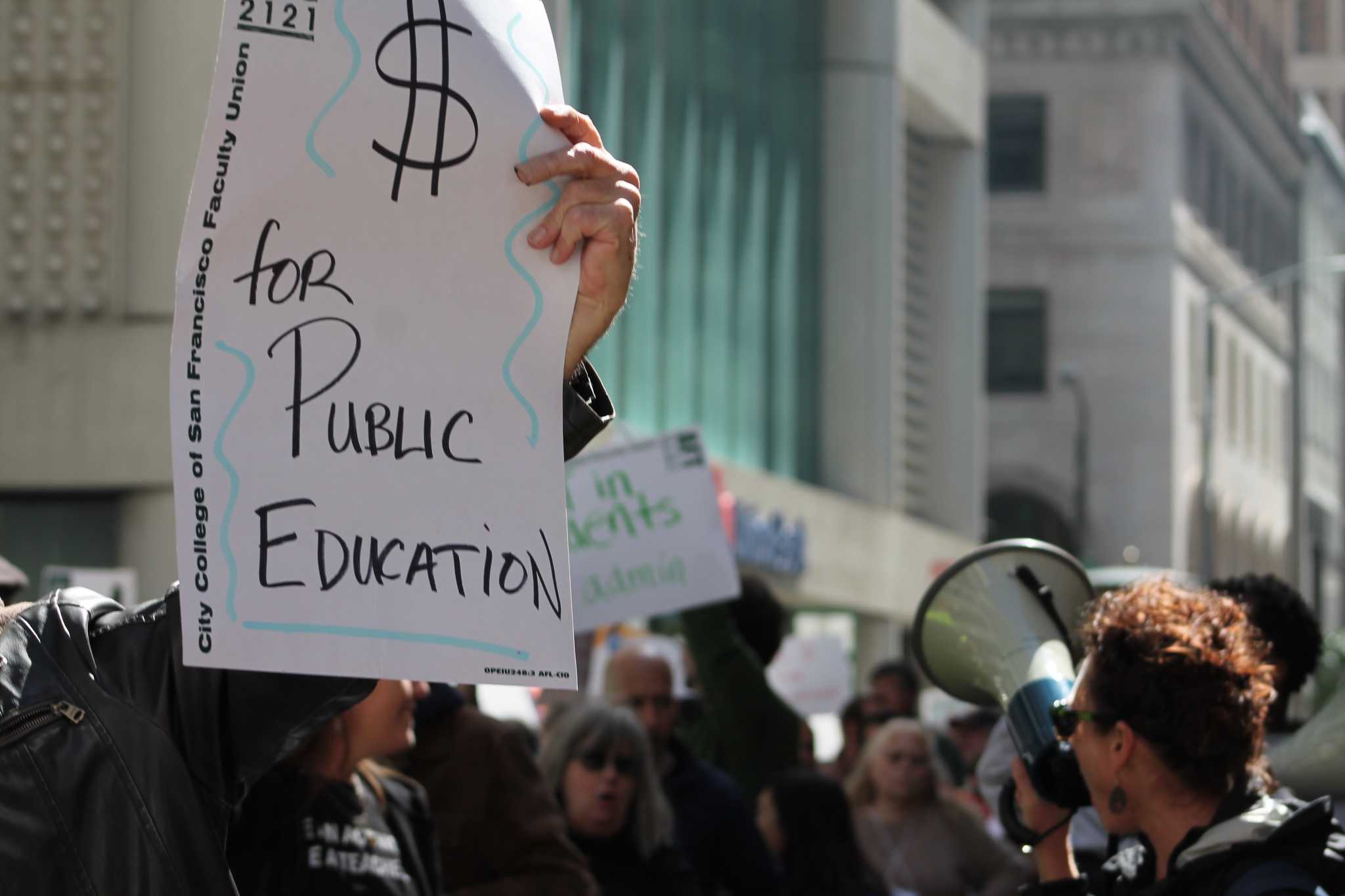 IMG_6684: A protestor holds a sign supporting money for public education as City College faculty, students, and community members march around him on March 11, 2016 in San Francisco, Calif. (Audrey Garces/The Guardsman)