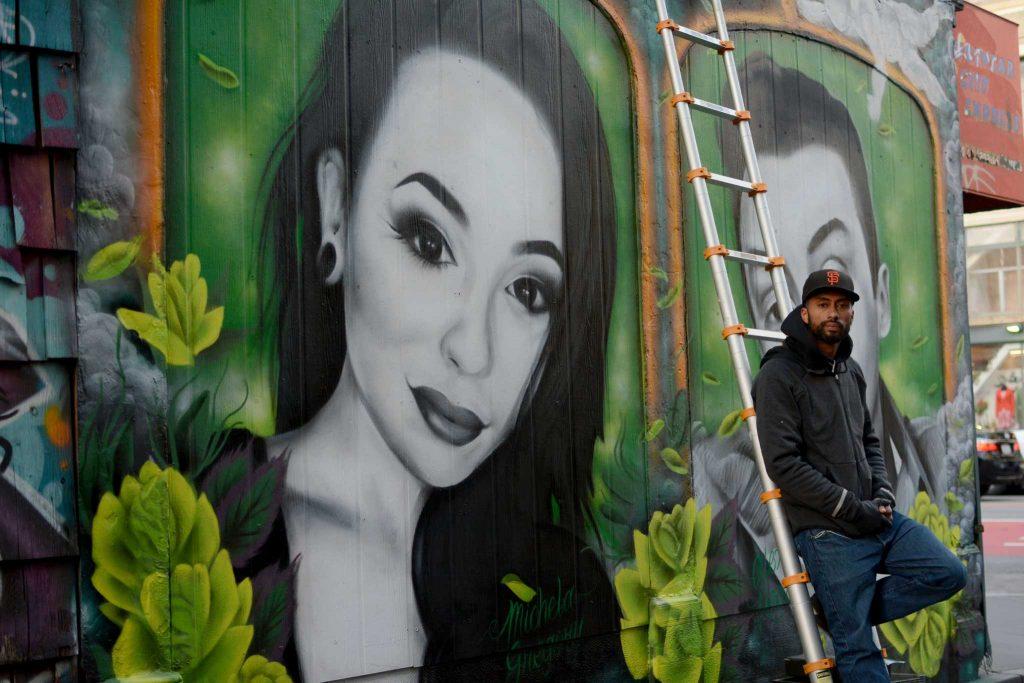 Mel Waters, 34, a muralist from San Francisco poses for a photograph to his mural of Michela Gregory, a former SF State student and her boyfriend Alex Vega on Friday, Feb. 24, 2017. (
Aaron Levy-Wolins/Xpress)