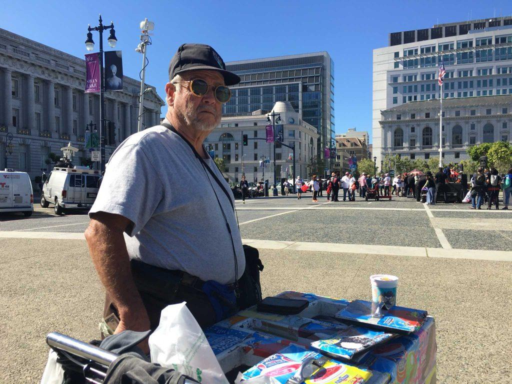 Ramiro Gutierrez Ortiz, 75, stands next to the A Day Without Immigrants protest in front of City Hall with his ice cream cart on May 1, 2017. (Gracie Ngo)