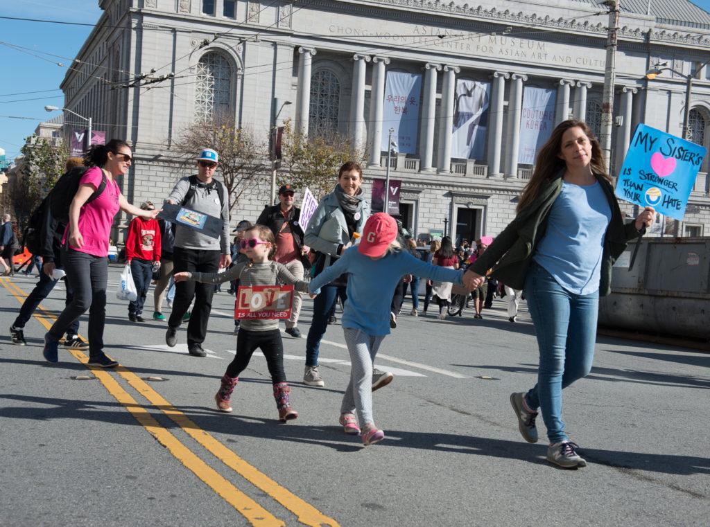 A mother walks with her two young daughters towards the Civic Center to find a nice area to stand in order to listen to speakers during Womens March in San Francisco, Saturday, Jan. 20, 2018. (Golden Gate Xpress/ David Rodriguez)