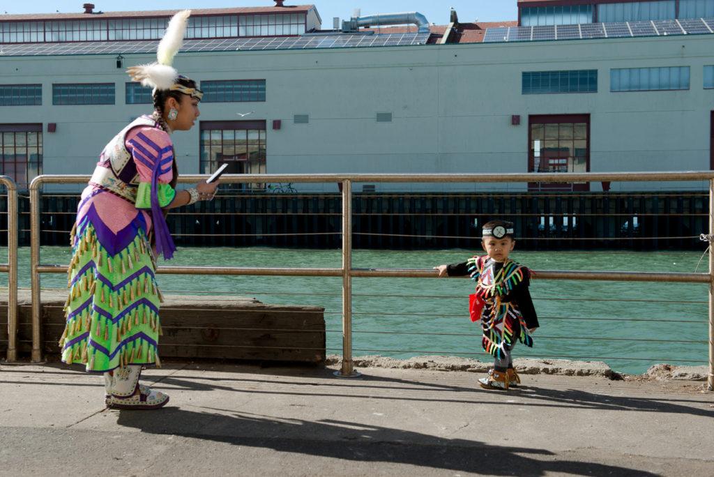 Celeste McGurk, left, takes photo of her 2-year-old son, Jaycen Llena, on the side of the Fort Mason Center in his cultural attire during the 2018 Two-Spirit POWWOW held at Fort Mason Center in San Francisco on Saturday, Feb. 3, 2018. (David M. Rodriguez/Golden Gate Xpress)