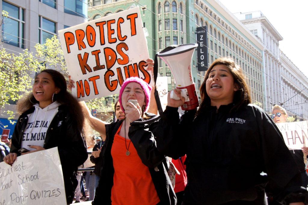 Norte Dame Belmont High School Students Feauint Saulala, left, Gia Elhihi, second left, Lucie Nash, second right, and Andrea Rios, left, leads crowd to march against gun control in San Francisco on Saturday, March 24, 2018.  (Aya Yoshida / Golden Gate Xpress)