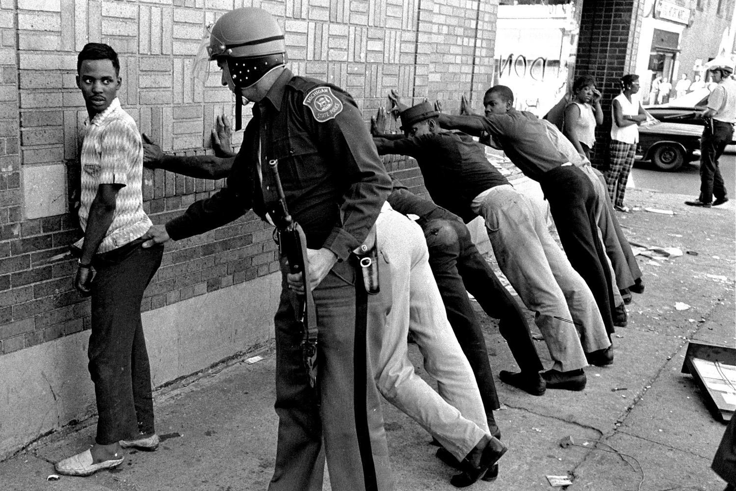 FILE - In this July 24, 1967 file photo, a Michigan State police officer searches a youth on Detroits 12th Street where looting was still in progress after the previous days rioting. The last surviving member of the Kerner Commission says he remains haunted that the panels recommendations on US race relation and poverty were never adopted, but he is hopeful they will be one day. Former U.S. Sen. Fred Harris says 50 years after working on a report to examine the causes of the late 1960s race riots he strongly feels that poverty and structural racism still enflames racial tensions even as the United States becomes more diverse. (AP Photo/File)