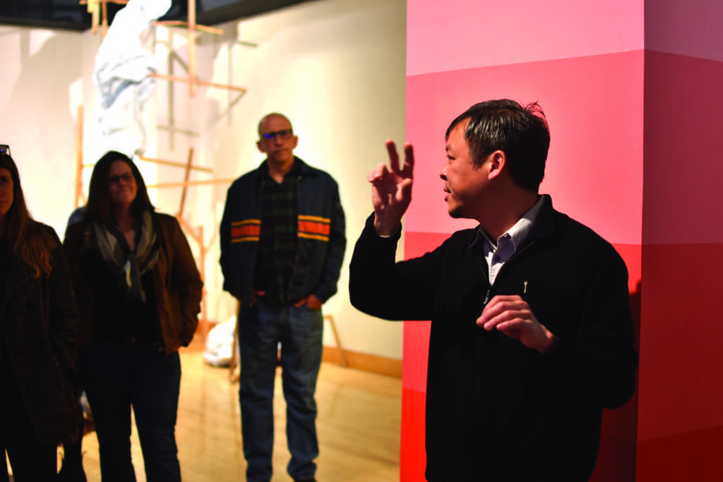 Kevin Chen
announces artists
and their work
while next to an
installation called
“Spectral Space”
in acrylic painting by Andrew
Shoultz during
the art gallery
opening of “Built
Environments” on
Saturday, Feb. 23,
2019.