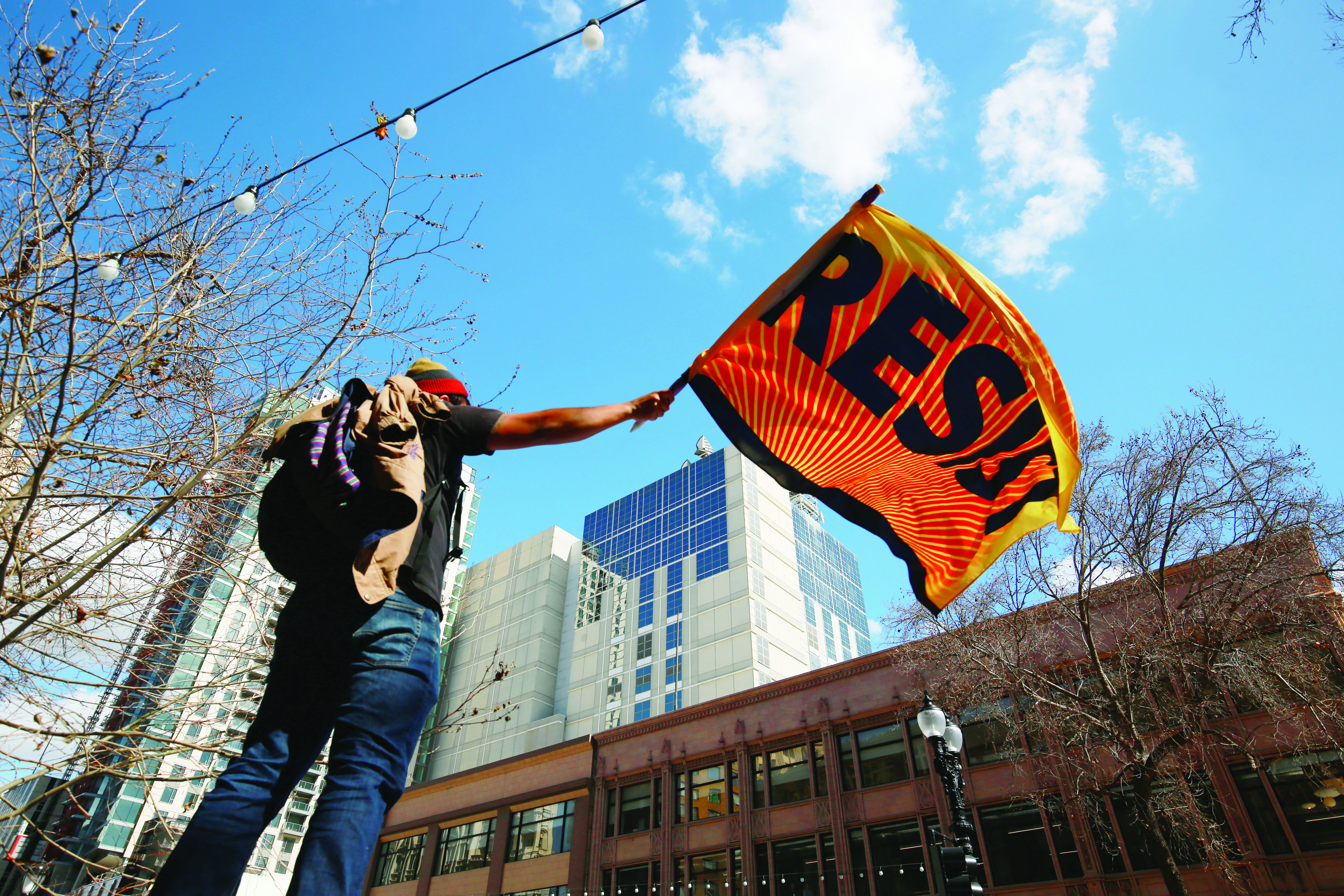 Eliseo Cañete, science teacher at Castlemont High School, waves a Resist flag over a city-wide rally in Downtown Oakland, California on the sixth day of the Oakland Teacher Strike Feb 28, 2019. (James Chan/Golden Gate Xpress)