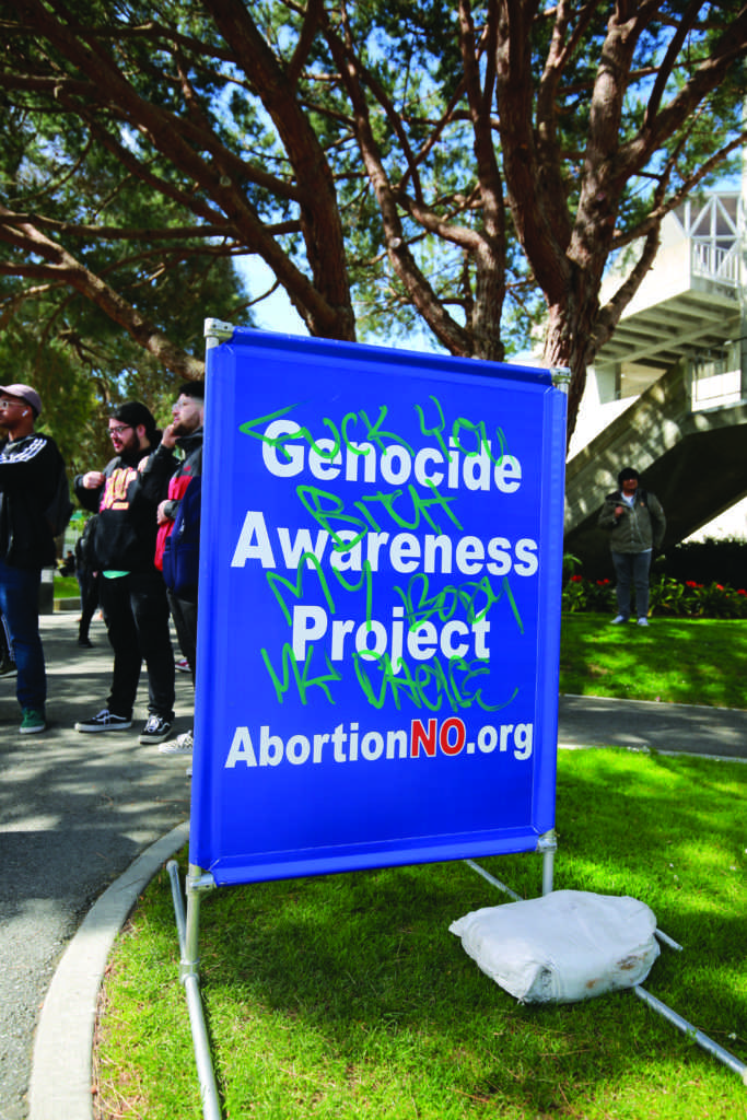 A Genocide Awareness Project sign with the words “Fuck you bitch my body my choice,” scrawled on it in front of the Cesar Chavez Center during an anti-abortion protest on Monday, April 15, 2019.(JAMES CHAN/ Golden Gate Xpress)