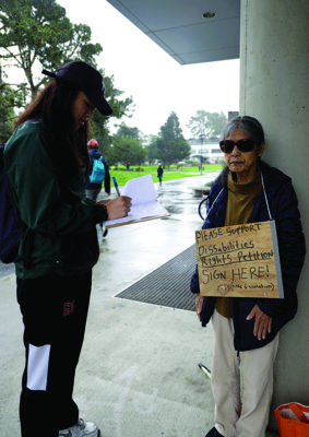 Eve Nguyen, pre-biology major, at San Francisco signs Miwa Ikema’s petition at the J. Paul Leonard Library on Dec. 2, 2019. (Photo by Paige Acosta / Golden Gate Xpress)