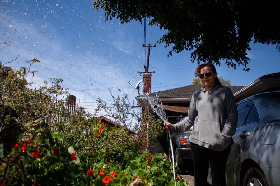 Janelle October waters her plants in her front yard in Pomona, California. (Maddison October / Golden Gate Xpress)