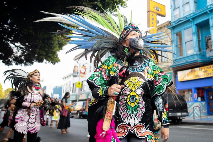 An Aztec dancer looks above the trees on 24th street, during a walk towards 24th and Folsom streets on Nov. 1, 2020. (Sebastian Mino-Bucheli / Golden Gate Xpress)
