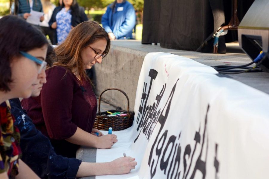 Emily Simmons, 24, a student experience architect for SF Hillel, writes a note to victims of the shooting at the Tree of Life synagogue in Pittsburgh, Pa., at a vigil held at Malcolm X Plaza in San Francisco, Calif. on Monday, Nov. 5, 2018. (Aaron Levy-Wolins/Golden Gate Xpress)