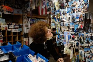 Stephanie Ernst Scott recounts one of the hundreds of stories behind the photos that line the entryway into Gus’ Discount Tackle. Customers and friends have built up the shrine-like collection over decades. (Avery Wilcox / Golden Gate Xpress)