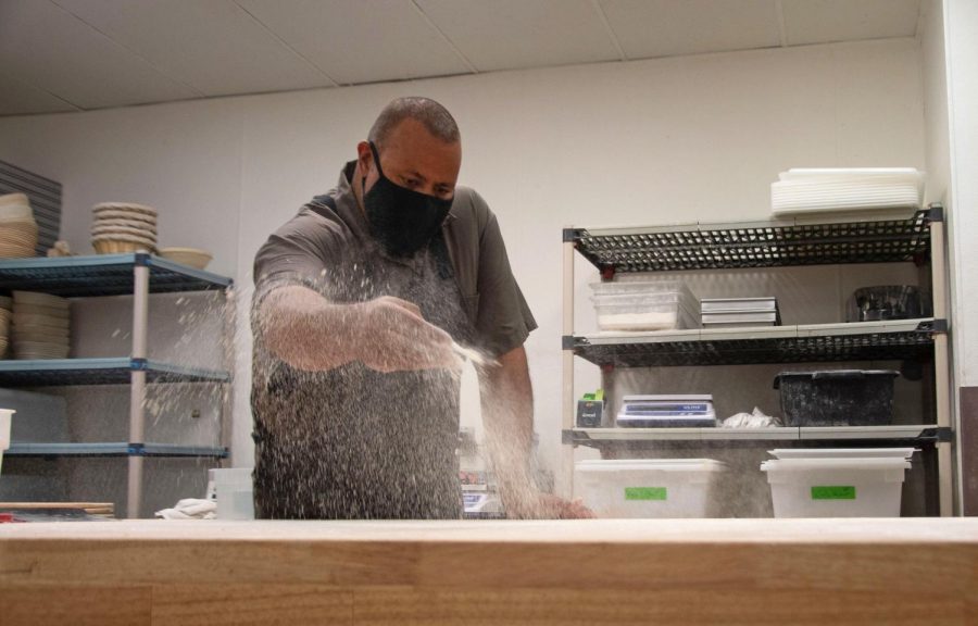 Azikiwee Anderson, founder of RizeUp Sourdough, sprinkles flour all over his workspace before he starts working with and shaping his dough in his North Beach baking space on Sept. 2, 2021. Each loaf is sized to be small enough to enjoy all at once if desired, but large enough to feel substantial and shareable. (Morgan Ellis/Golden Gate Xpress)