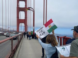 Protestor holds their sign for oncoming traffic to see on the Golden Gate Bridge on Sept. 25, 2022 during a protest against the . (Daniela Perez / Golden Gate Xpress) 