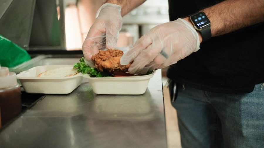 Mohammed Suleman, manager of Crave’s Birdhouse, prepares a fried chicken sandwich called “The Batman” which contains a fried chicken cutlet, barbecue sauce and ranch along with lettuce and tomatoes. (Miguel Francesco Carrion / Golden Gate Xpress) 