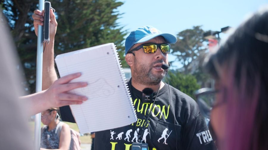 A born-again Christian protester who self-identifies as POG or “Preacher of God” debates with students in the Quad on Sept. 7. POG came to the SF State campus holding a banner that called various groups to “repent or perish.” (Miguel Francesco Carrion / Golden Gate Xpress)