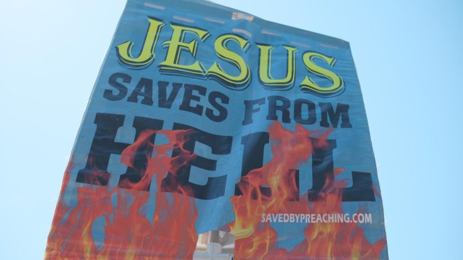 The man who self-identifies as POG. or “Preacher of God” holds a banner that states “Jesus saves from hell.” On the reverse side, the banner lists various groups that are called to “repent or perish.” The list includes gamers, lukewarm Christians and the LGBTQ community. (Miguel Francesco Carrion / Golden Gate Xpress)
