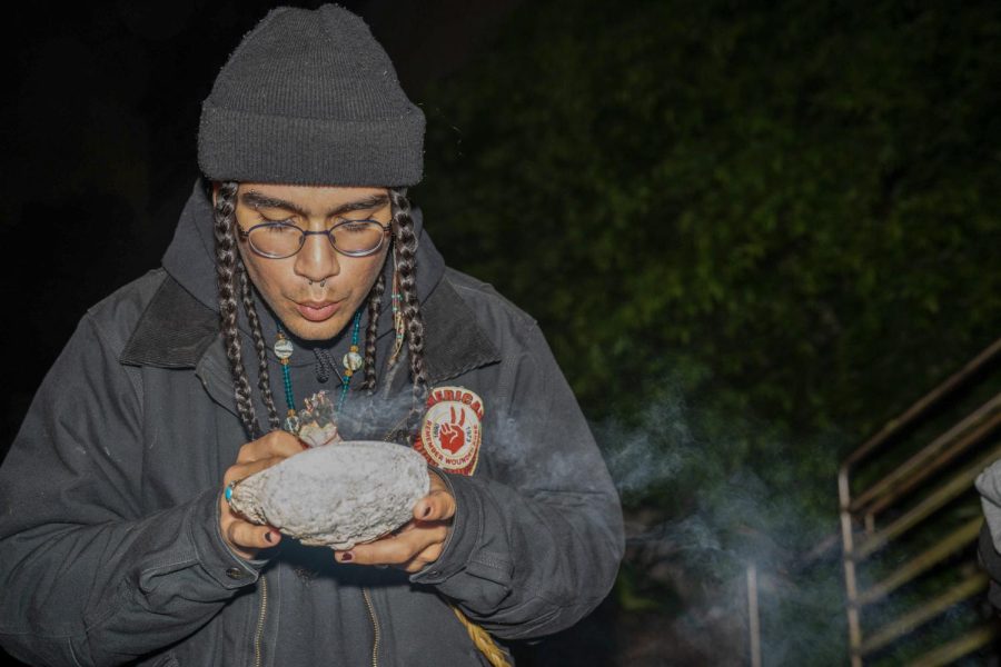  Elías Mathus, education facilitator for SKINS, ignites sage in an abalone shell at SF State on Oct. 10, 2022. Mathus carried the medicine while placing signs for protection. (Joshua Carter / Golden Gate Xpress)