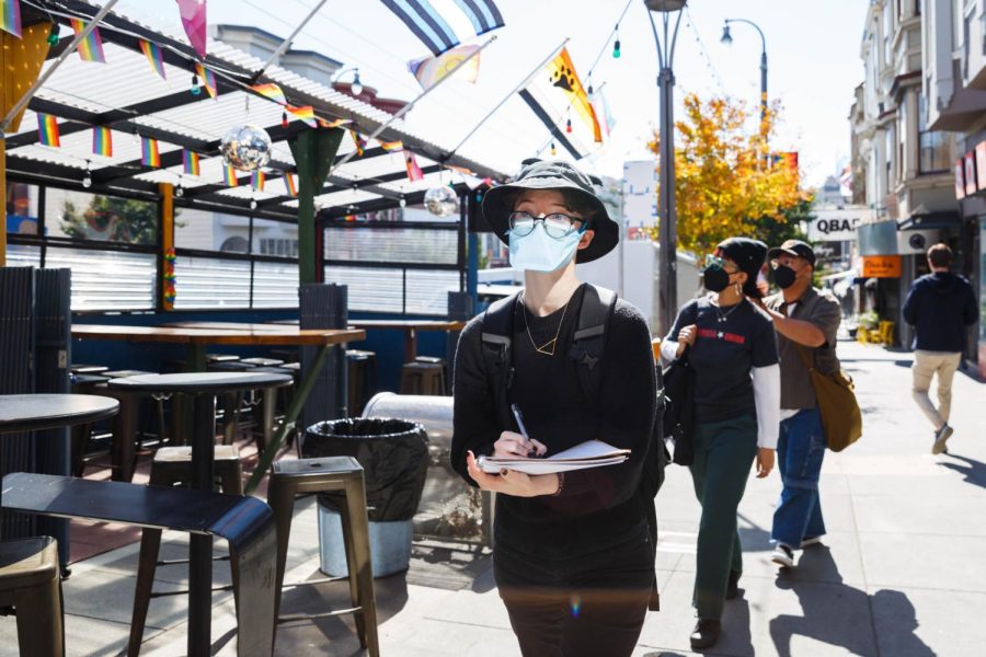 Cam Davis writes a piece of poetry while she walks in the Castro District on Oct. 7, 2022. Davis is enrolled in the Writing on Muni class in SF State’s Experimental College, where students go on different field trips in the city to write poems. (Juliana Yamada / Golden Gate Xpress)
