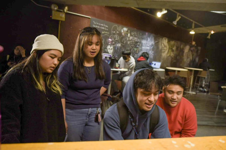 Students gather around Jonathan Flores while he plays the piano at The Depot inside the Cesar Chavez Student Center at SF State on Nov. 2, 2022. (Ashley Hayes-Stone / Golden Gate Xpress)