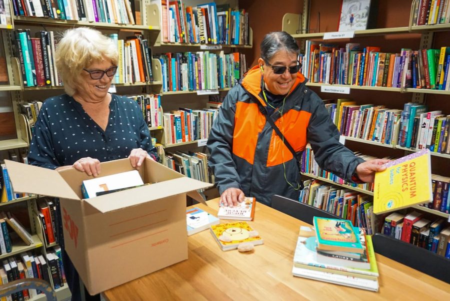 Barbara Loomis (left) manager of the used media and book store in the library at SF State, assists customer Rick Yuen (right) in finding children’s books for his grandkids on Dec. 2, 2022. (Tatyana Ekmekjian / Golden Gate Xpress)