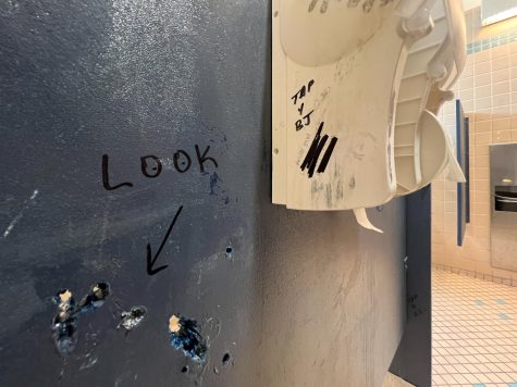 “LOOK” is written with an arrow pointing to peepholes in bathroom stalls of SF State’s Humanities Building on Oct. 19, 2022. Additional writing on the stall reads “TAP 4 BJ” and “ASIAN BTM.” (Myron Caringal / Golden Gate Xpress)