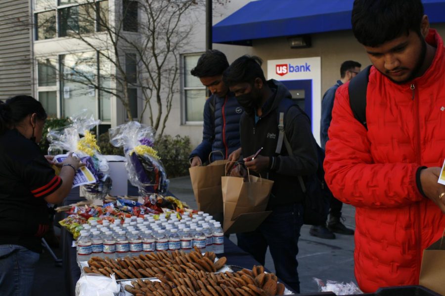 Students Aksh Pate (L) and Axat Vyas (R) take complimentary sweets and snacks outside SF State’s student housing Village C on Feb. 8, 2023. (Tam Vu / Golden Gate Xpress)