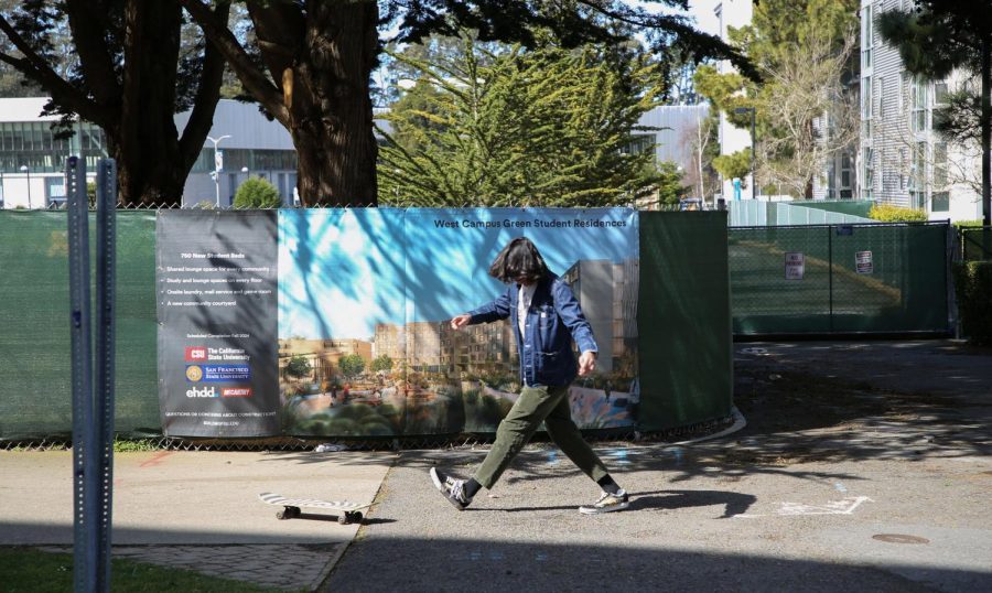 Astronomy student, Cade Forero, walks after his skateboard in front of the construction gate of West Campus Green at SF State on Feb. 27, 2023. (Tam Vu / Golden Gate Xpress)