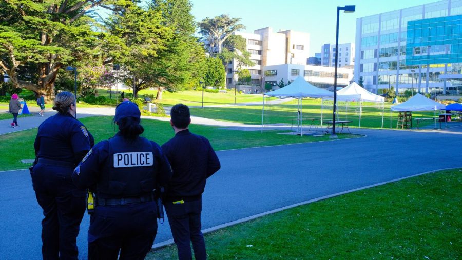 Two campus police officers along with Chris Trudell, associate dean of students,  stand in the SF State quad on Wednesday, April 19, 2023 as they survey the area. There was talk of TPUSA hosting their event in the quad after the university told them that the school would be unable to accommodate their estimated  800 attendees. (Miguel Francesco Carrion / Golden Gate Xpress) 
